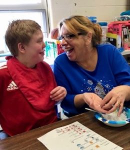 Staff helping student make snowballs.